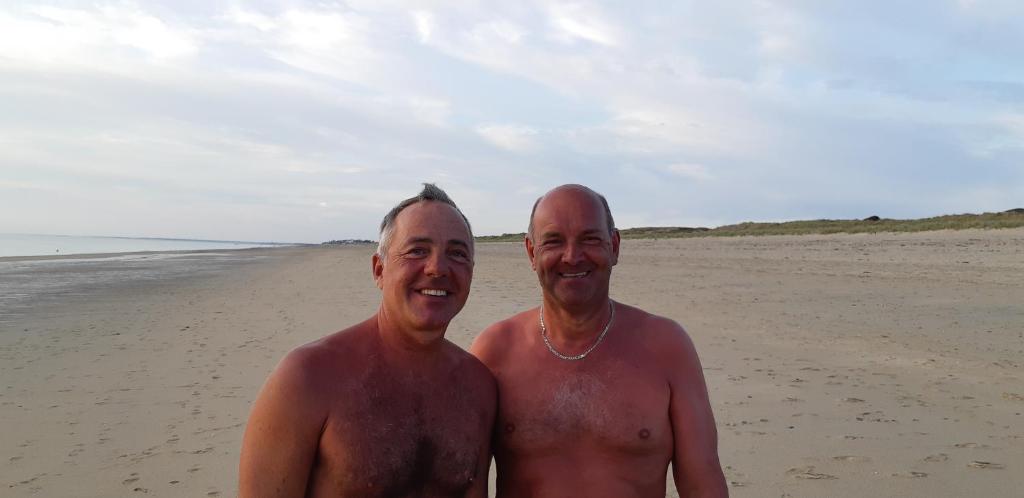 Dos hombres posando para una foto en la playa en Colocation ggayfriendly chez l'habitant près de la plage naturiste de Granville, en Bréville-sur-Mer