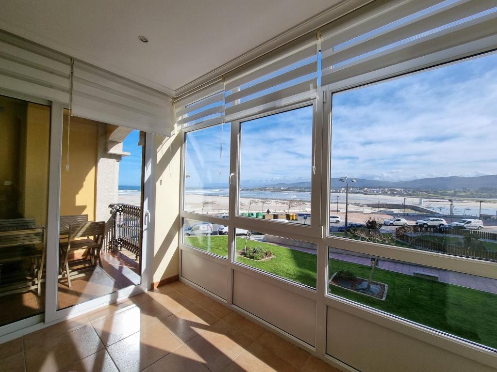 Habitación con ventanas grandes con vistas a la playa. en Apartamentos Rapadoira, en Foz
