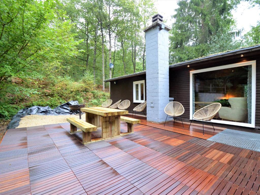 une terrasse en bois avec une table de pique-nique et des chaises dans l'établissement Enticing Chalet with Private Terrace, à Trou du Diable