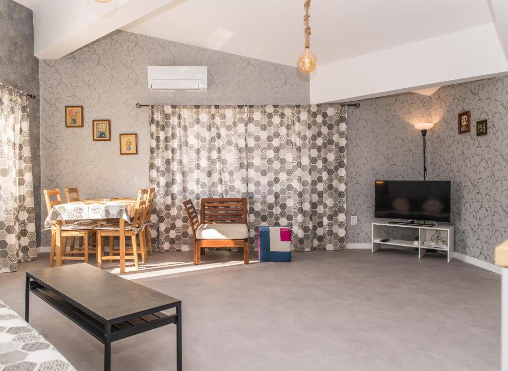 Una sala de estar con un televisor y una mesa y sillas. en Miramar Balchik Apartment 10, en Balchik