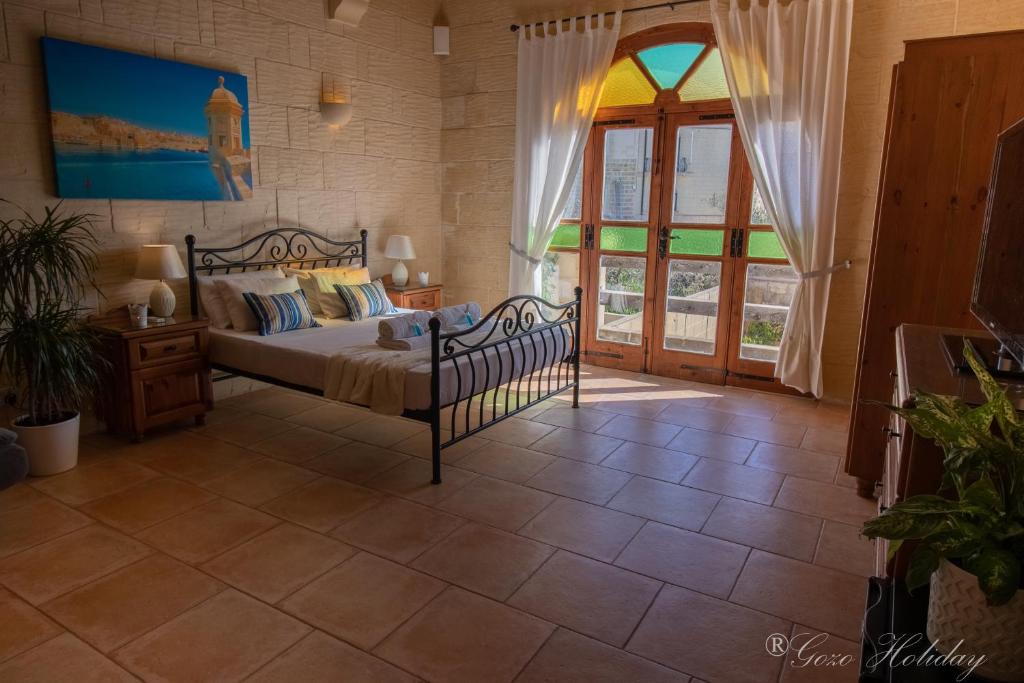 a bedroom with a bed and a large window at Lellux Qala in Qala