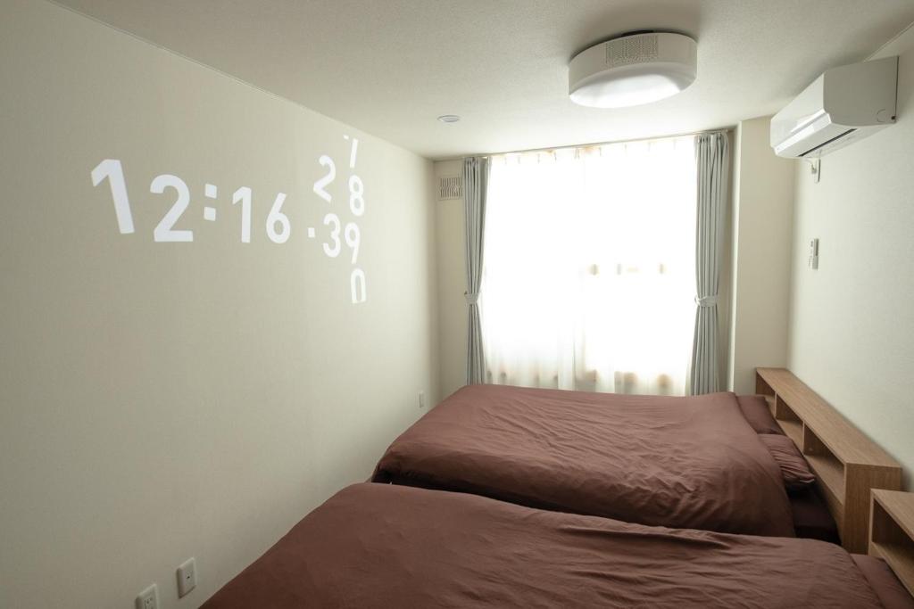 a bedroom with two beds and a clock on the wall at TKD Asahikawa - Vacation STAY 24510v in Asahikawa