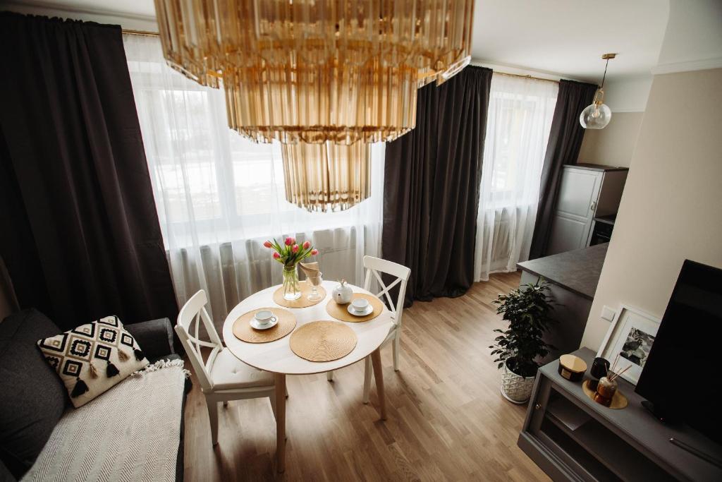 a living room with a table and chairs and a chandelier at Cesis WELCOME apartment in Cēsis