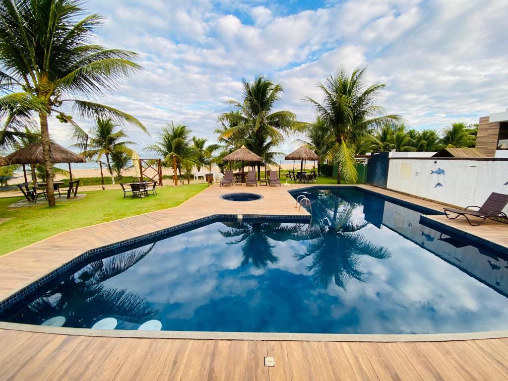 una piscina con vistas a la playa y a las palmeras en Itacimirim Summer Houses 2/4 Pé na areia, en Camaçari