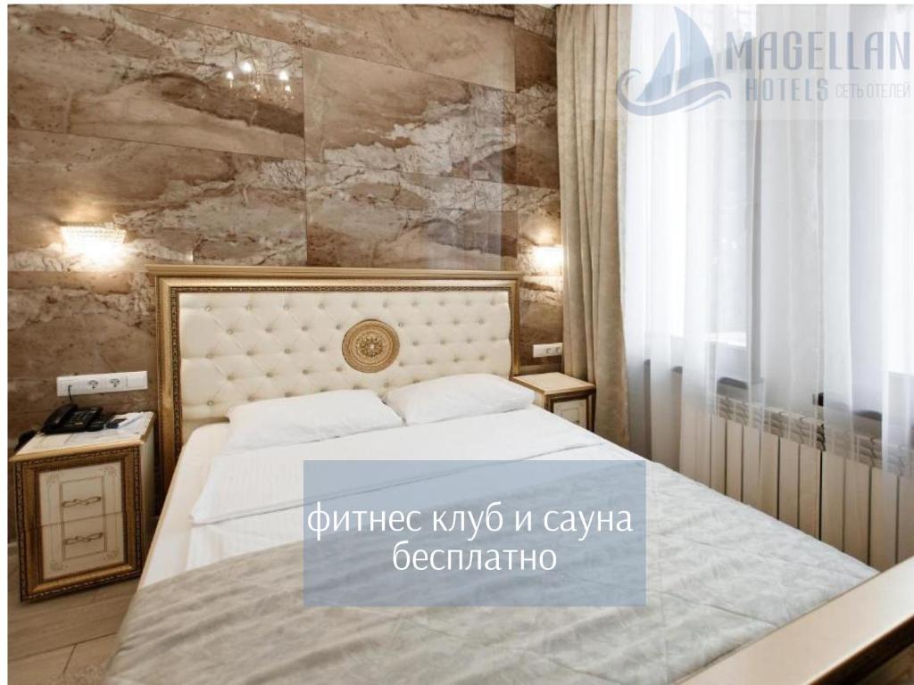 1 dormitorio con cama blanca y pared de piedra en Магеллан Один Сочи, центр en Sochi