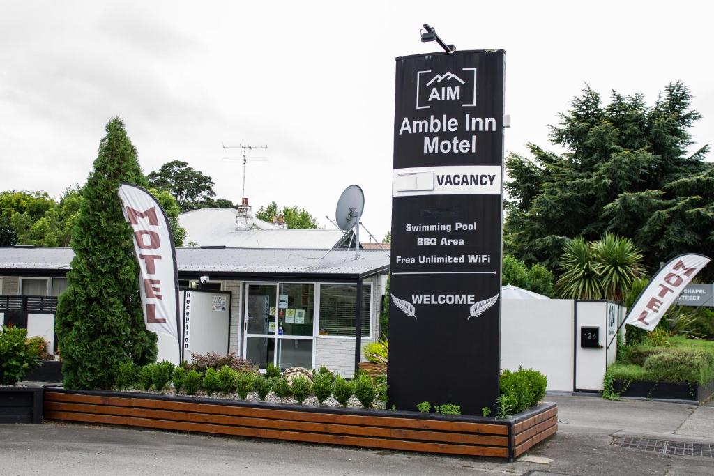 um sinal para um motel Apple Inn em frente a um edifício em Amble Inn Motel em Masterton