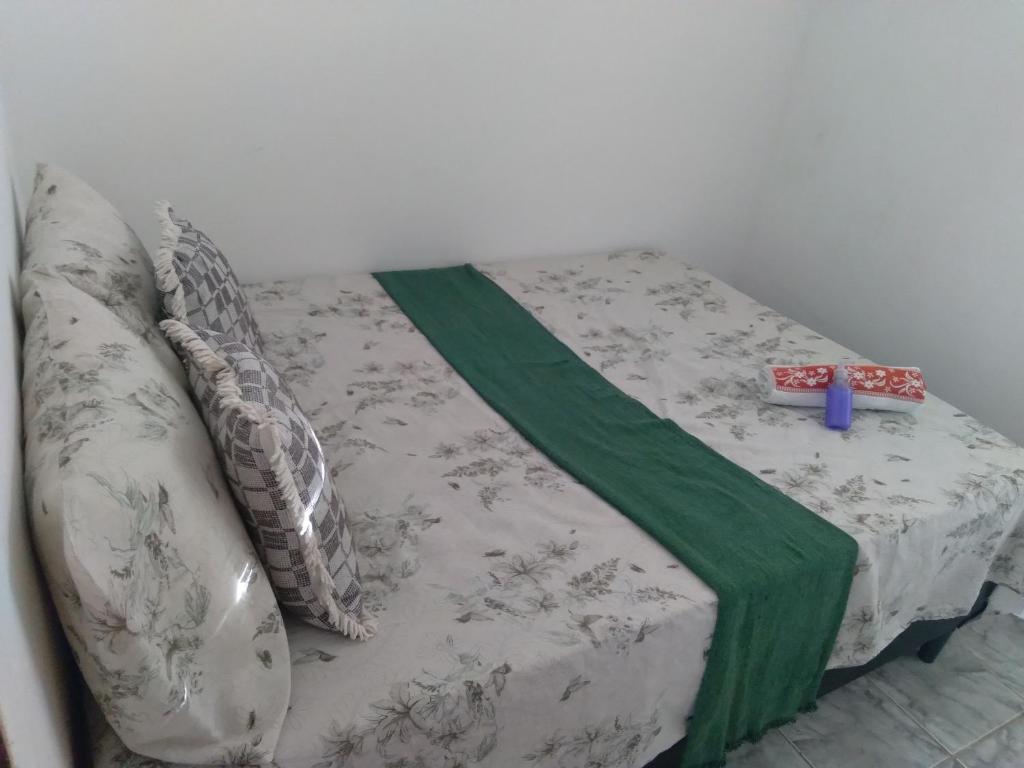 a bed with a green and white blanket on it at Quarto Bem vindo in João Pessoa