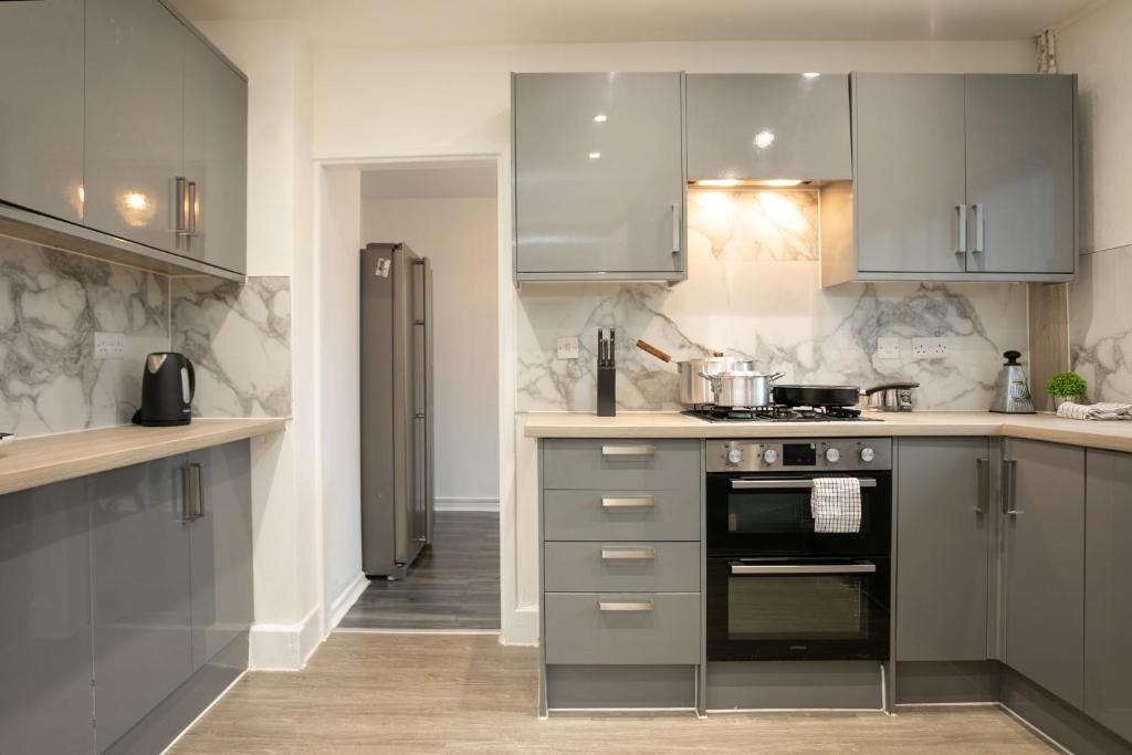 una cocina con electrodomésticos de acero inoxidable y armarios grises en Nottingham Top Serviced Home - Chayil Experts, en Nottingham