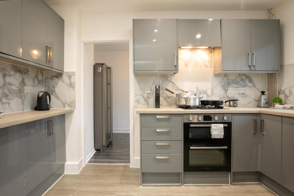 a kitchen with stainless steel appliances and gray cabinets at Nottingham Top Serviced Home - Chayil Experts in Nottingham