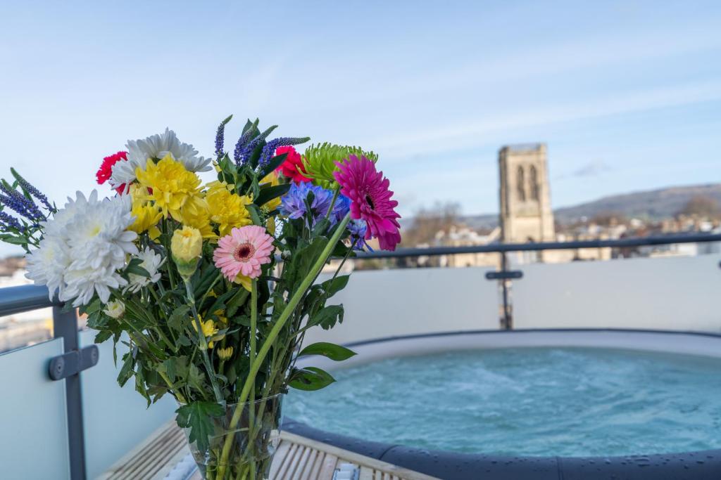 un jarrón de flores sentado en una mesa junto a una piscina en Central Penthouse with Hot Tub & Views 22, en Cheltenham