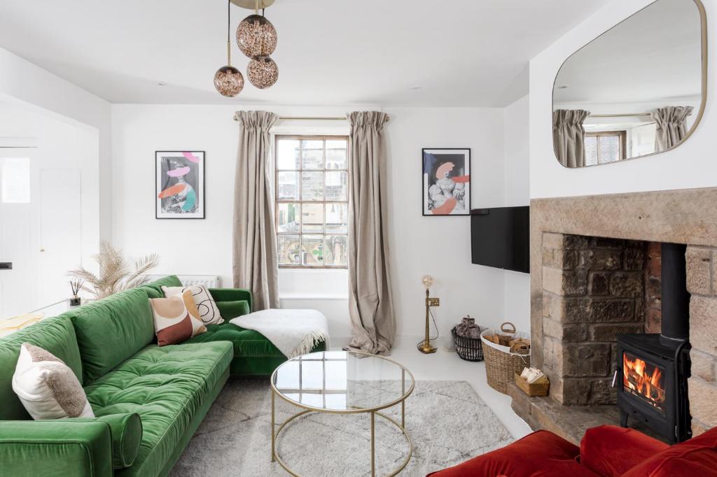 uma sala de estar com um sofá verde e uma lareira em Luxe Design - Grade II Listed Cottage - Heart of Alnwick em Alnwick