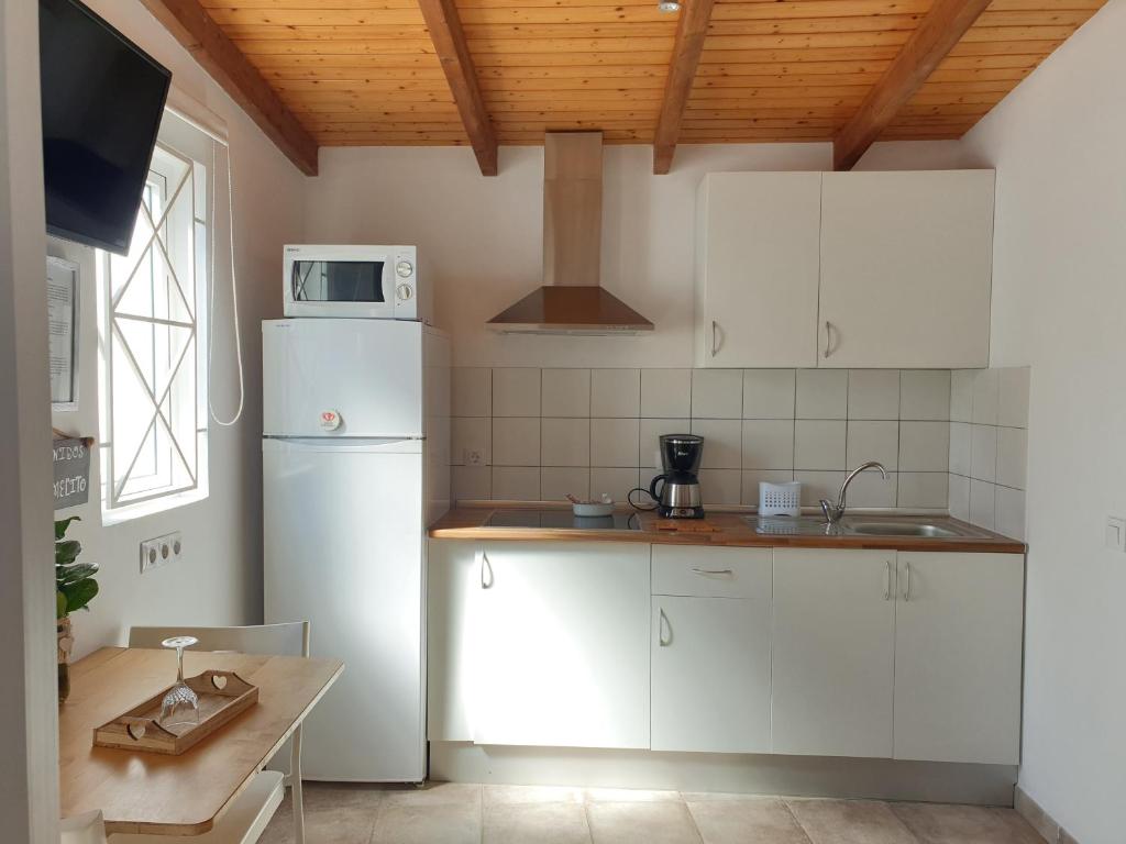 uma cozinha com armários brancos e um frigorífico branco em El Caramelito 1 em Maspalomas