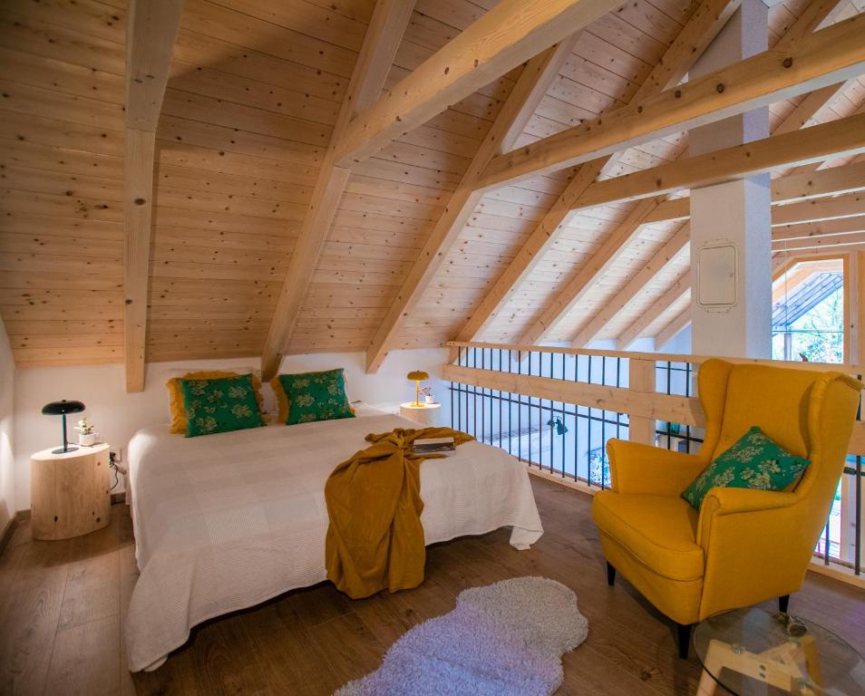 a bedroom with a bed and a yellow chair at Boglya Ökoház in Ozora