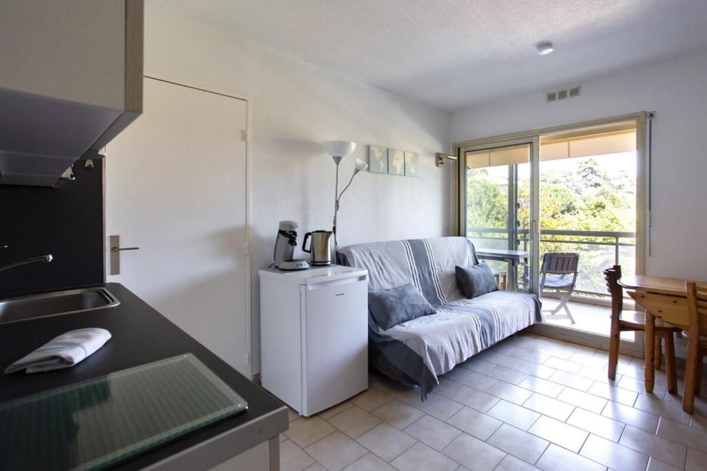 uma cozinha e sala de estar com um sofá e uma mesa em Charming Apartment in The City Center With Furnished Terrace pool & Garage em Cagnes-sur-Mer