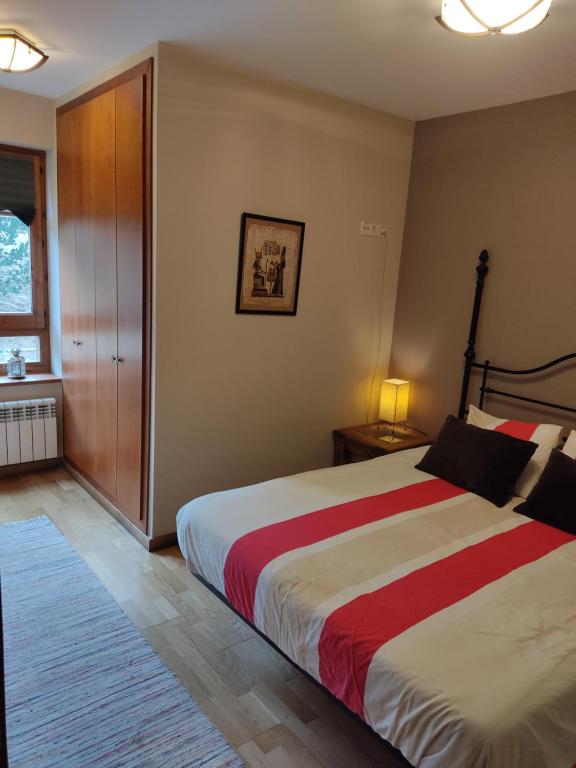 a bedroom with a large bed with a red and white blanket at Apartament de Luxe a Port del Comte in La Coma i la Pedra