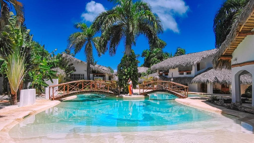un puente sobre una piscina en un complejo con palmeras en Paradiso del Caribe en Las Galeras