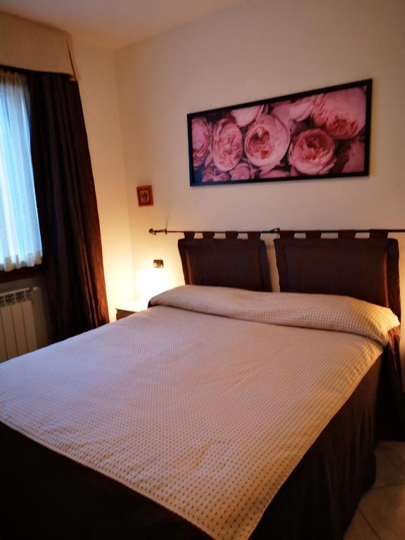 Schlafzimmer mit einem Bett mit rosa Rosen an der Wand in der Unterkunft Residence SANTA CROCE Delebio Provincia di Sondrio in Sondrio