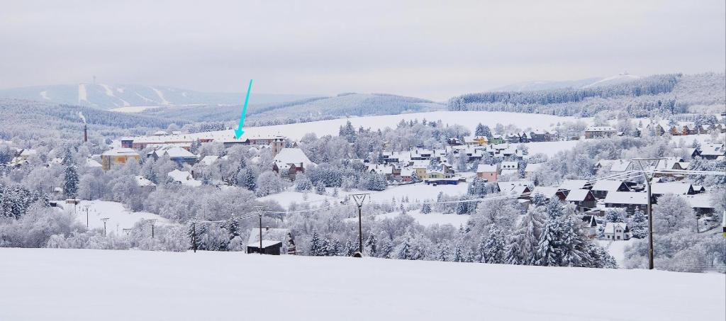 een besneeuwde heuvel met een stad in de verte bij Apartmán Kovářská u Klínovce in Kovářská