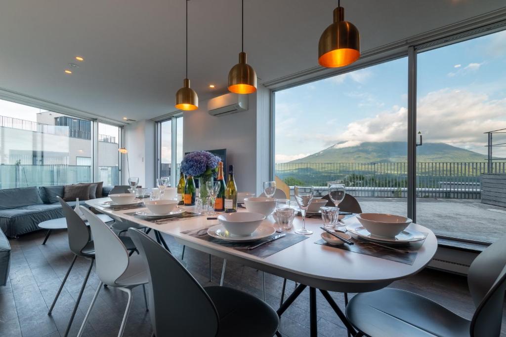 a dining room with a table and chairs and a large window at Kira Kira Suites by H2 Life in Niseko