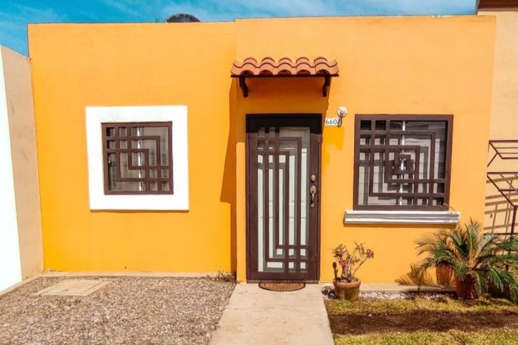 a yellow house with black doors and windows at Hogar tranquilo, cerca de marina y plaza comercial in Mazatlán