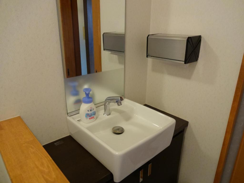 a bathroom with a white sink and a mirror at Jizokan Matsuya Ryokan in Nagano