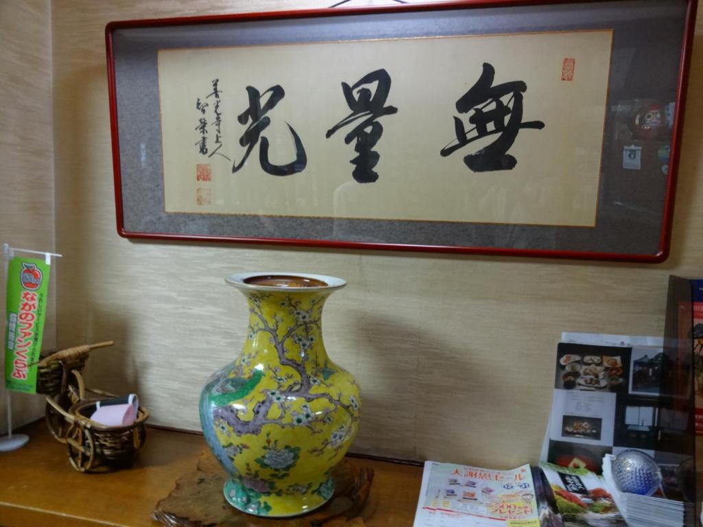 a vase sitting on a table in front of a painting at Jizokan Matsuya Ryokan in Nagano