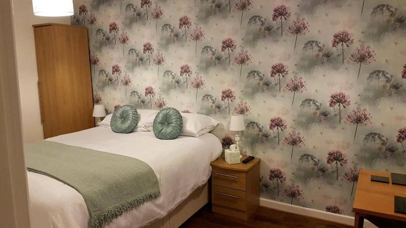 a bedroom with a bed with a floral wallpaper at Bell Inn in Evesham