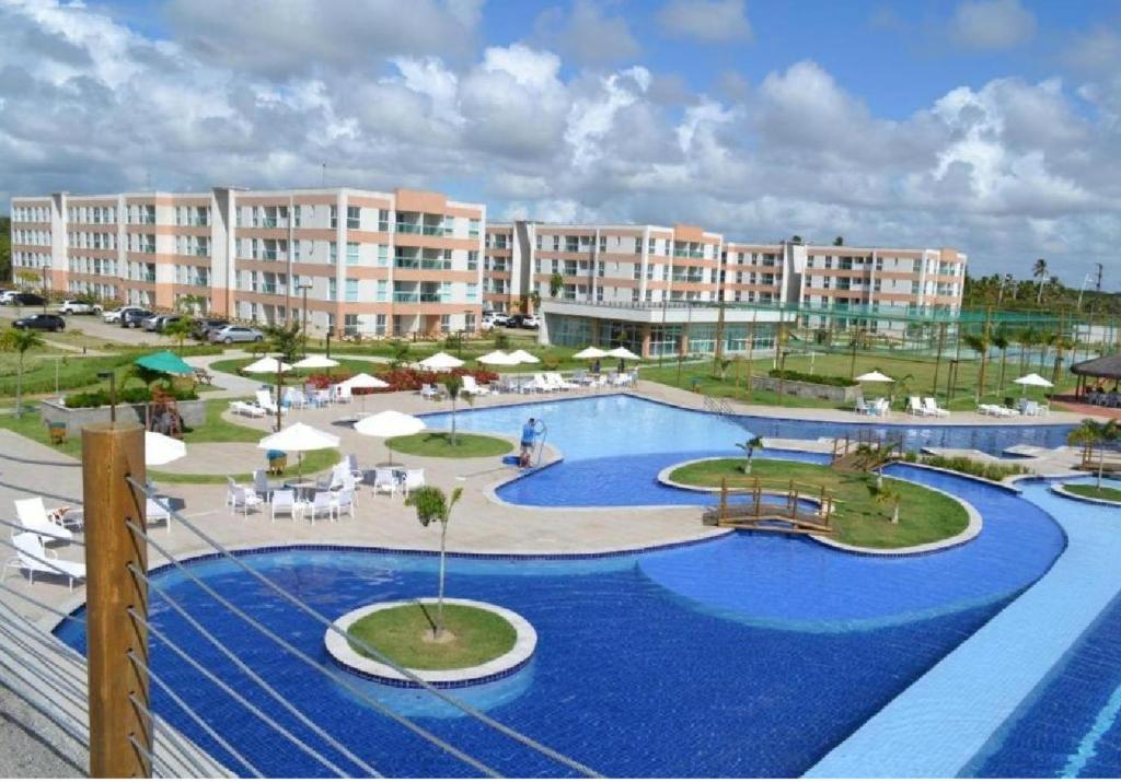 a resort with a large pool with chairs and umbrellas at Muro alto Flat Porto de Galinhas in Porto De Galinhas