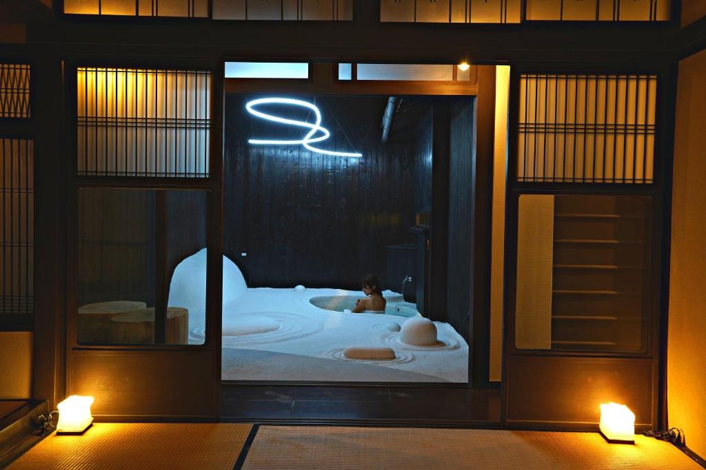 una persona in una vasca da bagno in una stanza con luci di Kiraku Kyoto Aneyakoji a Kyoto