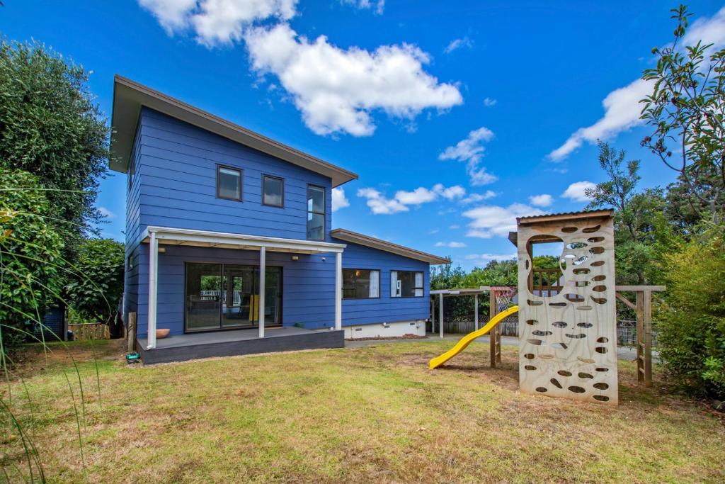 een blauw huis met een glijbaan en een speeltuin bij Taranui Escape - Mangawhai Heads Holiday Home in Mangawhai