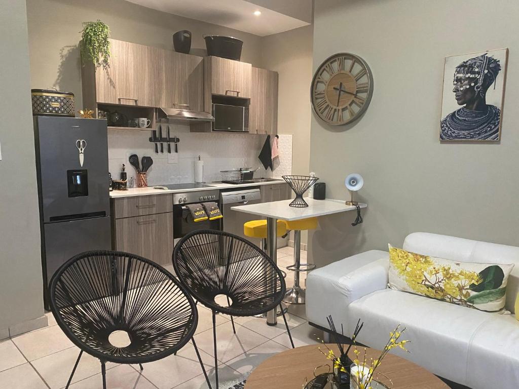 a kitchen and a living room with a couch and a table at Lovely Rosebank 1-bedroom condo with pool & cinema in Johannesburg
