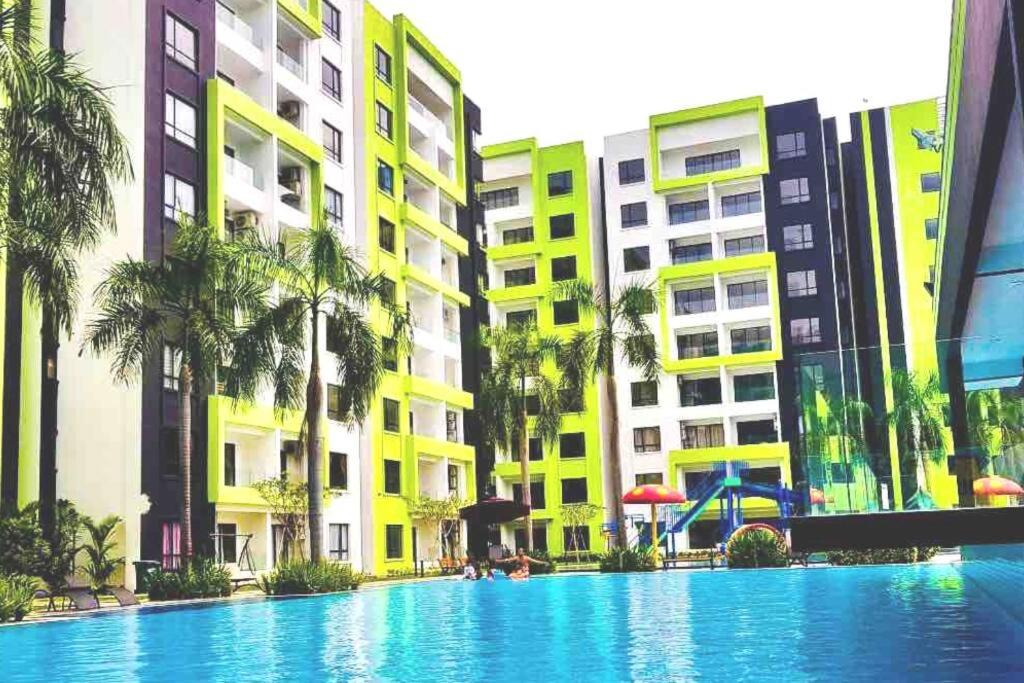 a swimming pool in front of buildings with palm trees at Manhattan Condo Ipoh with Water Park and Pool View in Ipoh