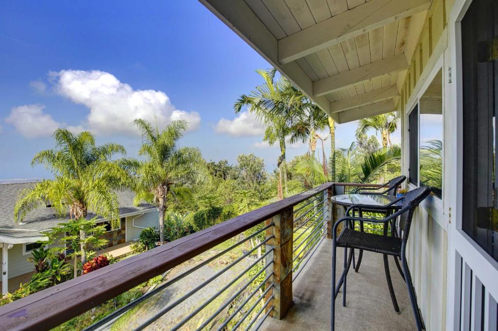 a balcony with a chair and palm trees at Charming Kailua-Kona Apartment Near Hiking and Golf! in Kailua-Kona