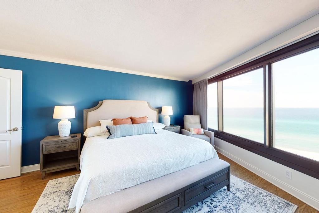 a bedroom with blue walls and a bed with a large window at Beachside II #4293 in Destin