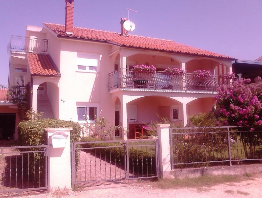 una gran casa blanca con una valla y flores en Apartment Tanja, en Vrsar