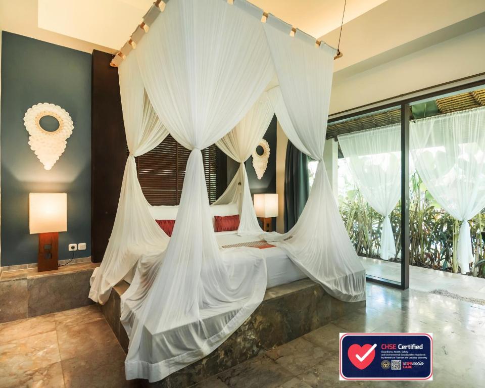 a bedroom with a canopy bed with white drapes at Karmagali Suites Adults only & Private Pool Family Villas in Sanur