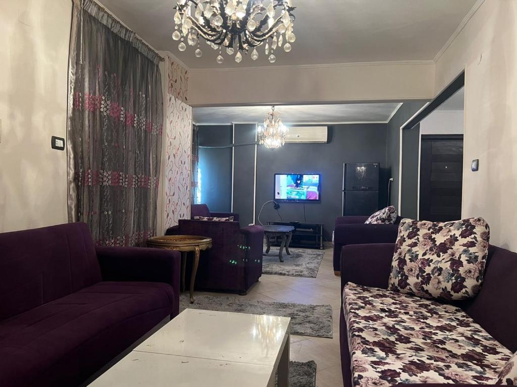 uma sala de estar com mobiliário roxo e um lustre em Family Apartment in Nasr City no Cairo