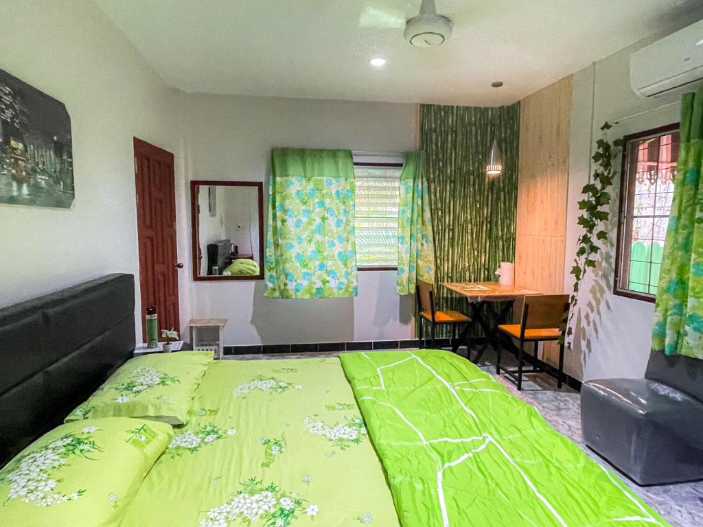 sypialnia z zielonym łóżkiem i stołem w obiekcie H&Q Bangtao Rooms w mieście Bang Tao Beach