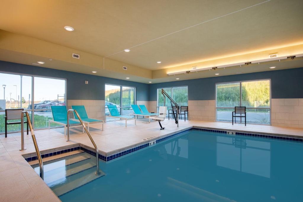 a large swimming pool with blue chairs and tables at Holiday Inn Express & Suites - Beloit, an IHG Hotel in Beloit