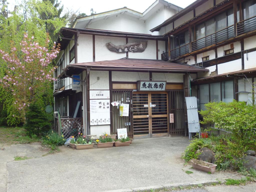 un bâtiment avec un panneau à l'avant dans l'établissement Uotoshi Ryokan, à Yamanouchi