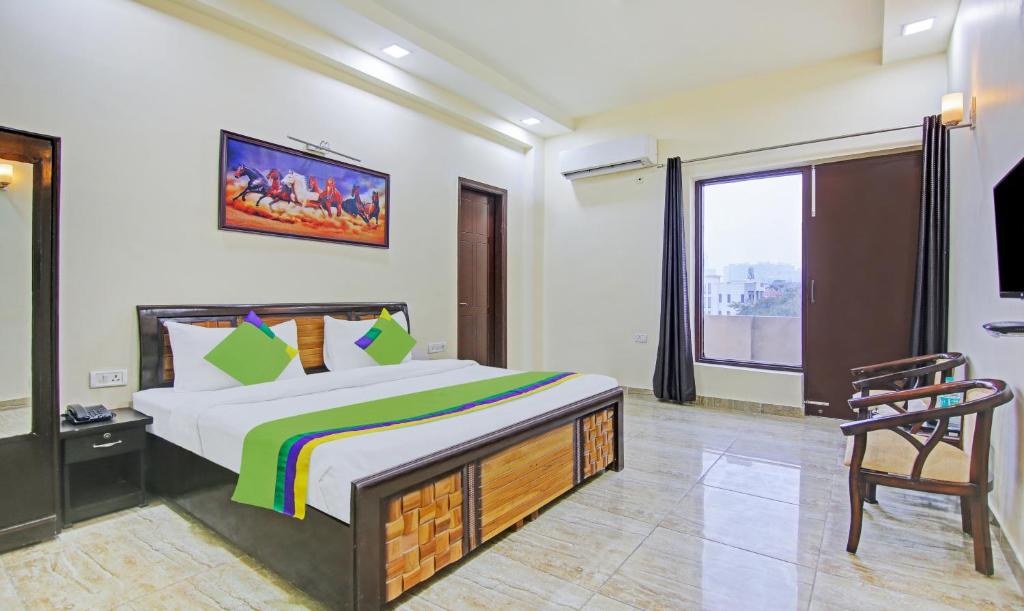 a bedroom with a bed and a chair and a window at Treebo Trend Amaya Inn Sector 72 in Noida