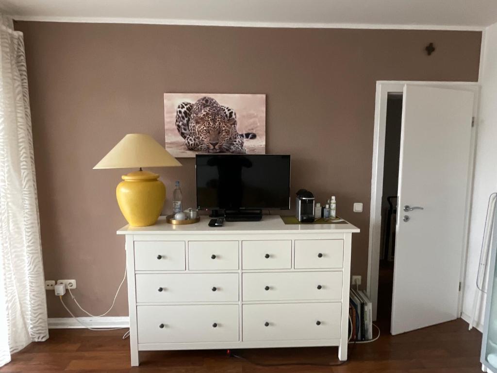a bedroom with a white dresser with a tv on top at wohnliches , behagliches Zimmer mit Balkon und wifi in Mönchengladbach