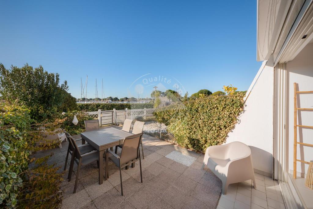 un patio avec une table et des chaises sur un balcon dans l'établissement AS20113 - P2 Cabine, jardin avec belle vue sur le chenal et les bateaux, au Grau-du-Roi