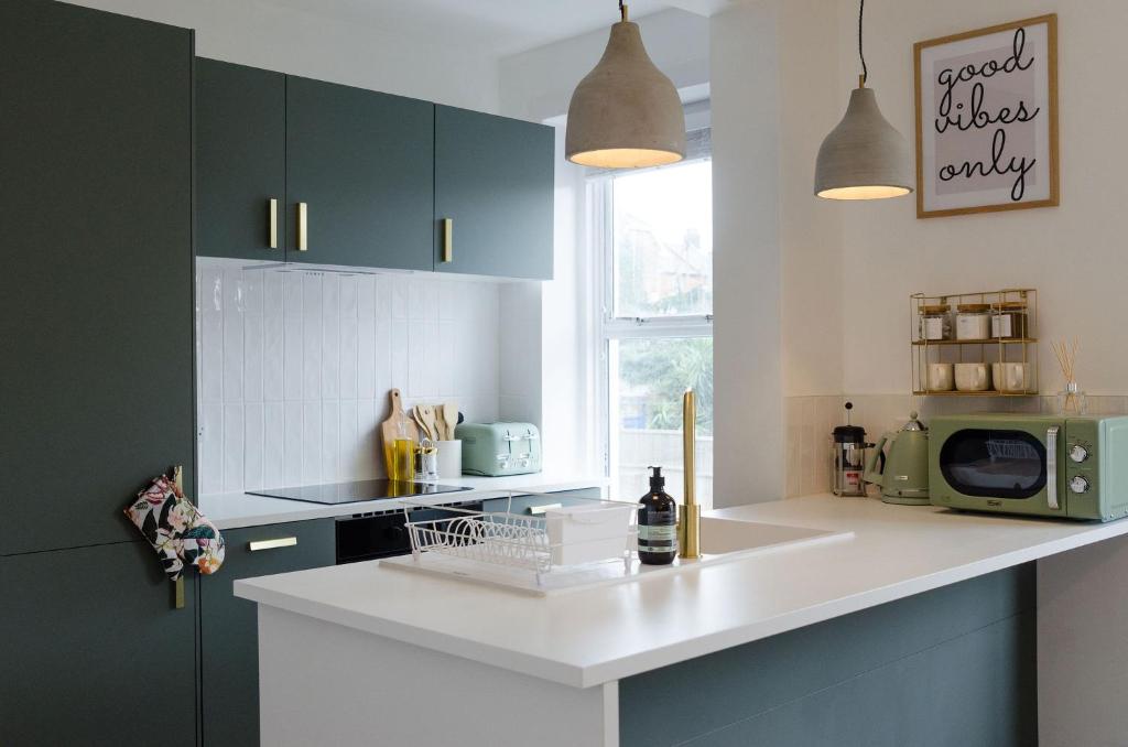 a kitchen with green cabinets and a white counter top at Central Chic Margate Apartment, edge of Old Town! in Kent