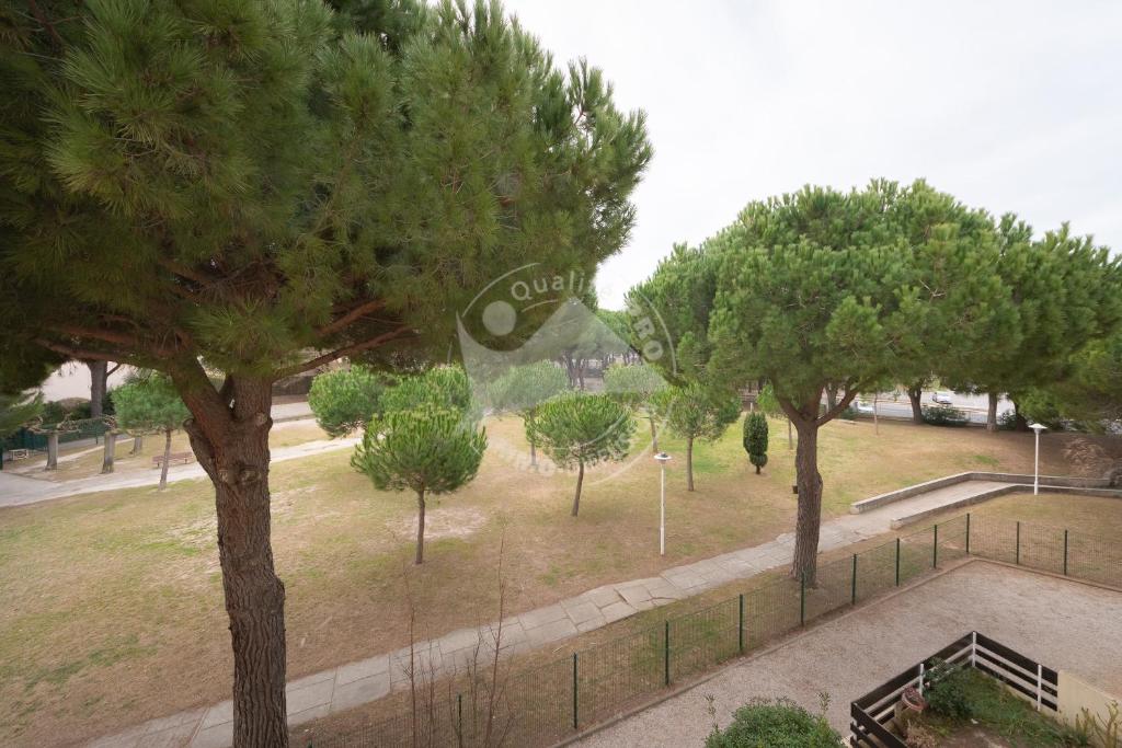 un parc avec des arbres et un panneau en arrière-plan dans l'établissement AS21600 - P2 Cabine à 200m de la plage avec parking privatif, au Grau-du-Roi