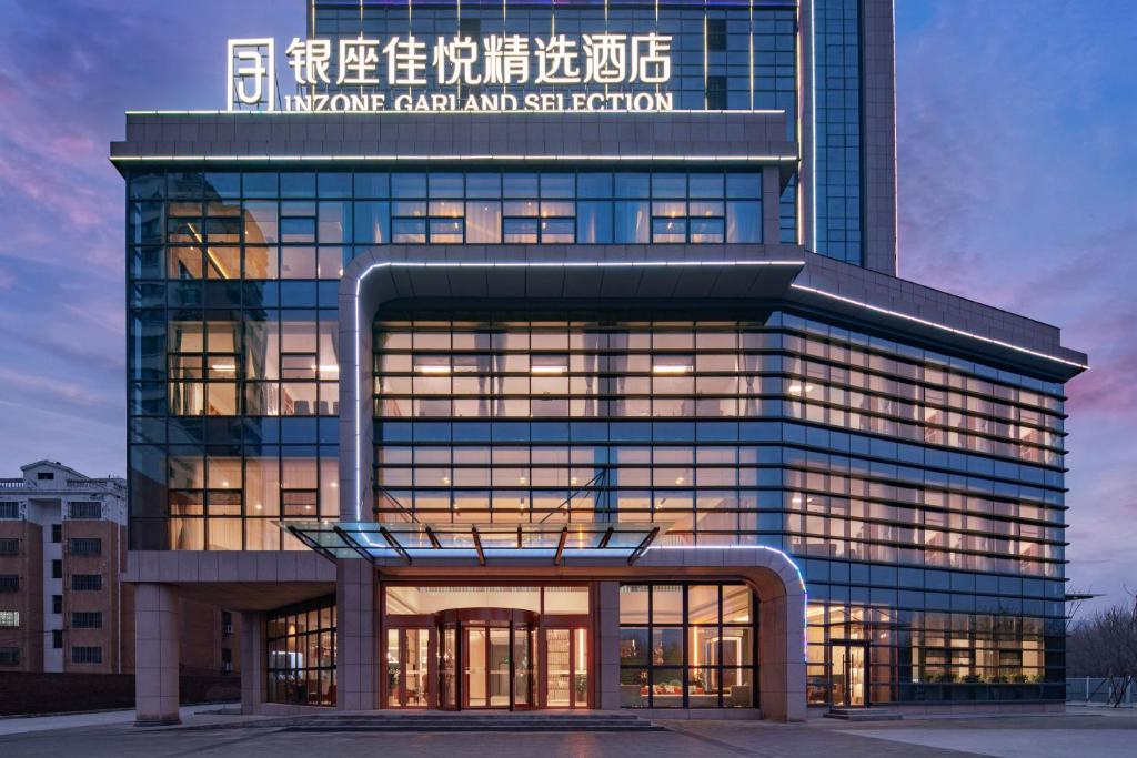 um grande edifício de vidro com uma placa em 银座佳悦精选酒店冠县冠宜春路店 em Kwanhsien