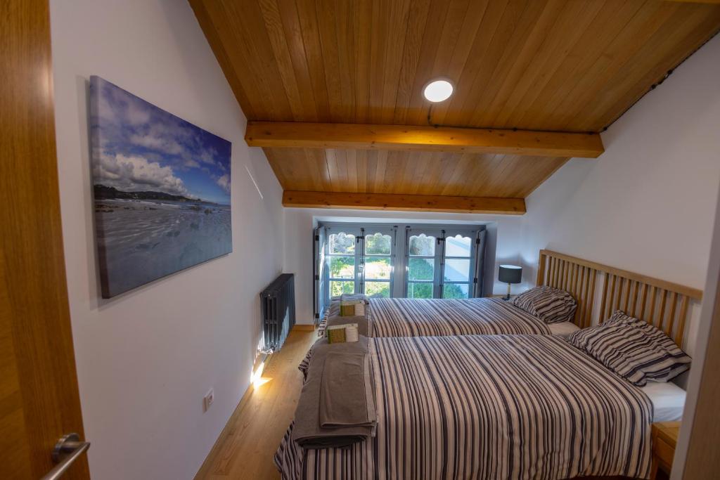 a bedroom with two beds and a tv on the wall at Casa Alameda 23 de Casas Das Figueiras en Ría Eo-Ribadeo in Castropol