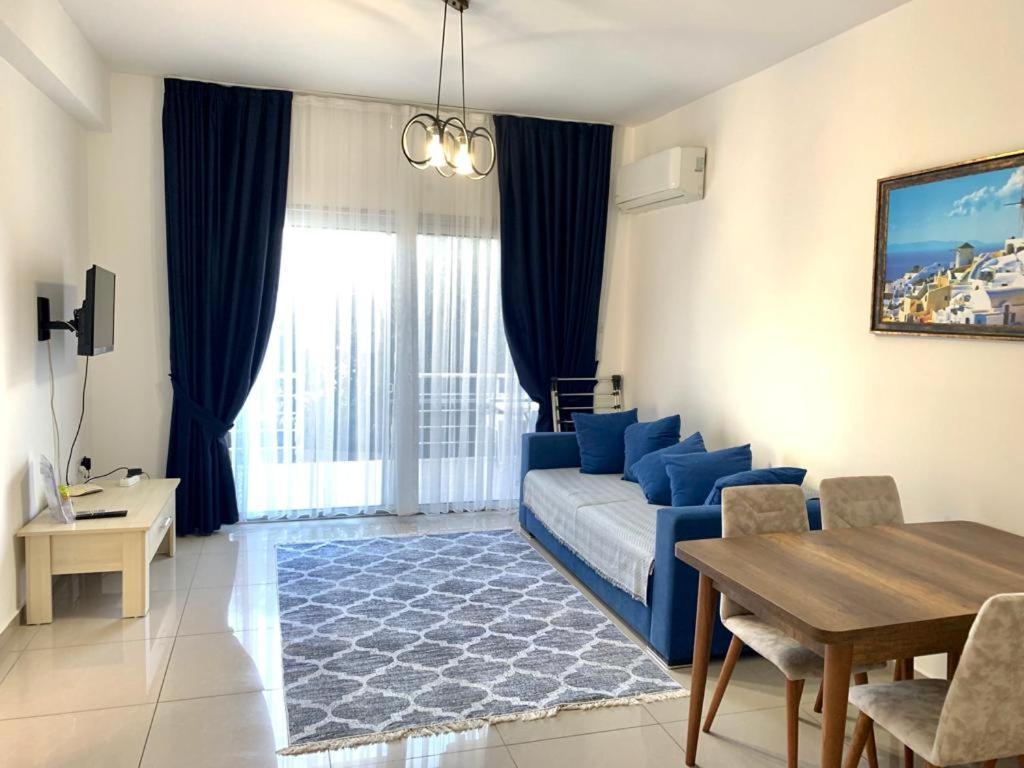 ein Wohnzimmer mit einem blauen Sofa und einem Tisch in der Unterkunft Beautiful & Quiet Two-Bedroom Apartment with Private Garden Lukomorye C1 in Kyrenia