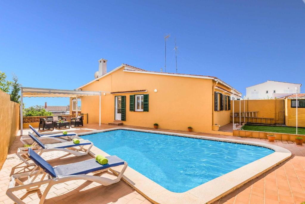 a swimming pool with two chairs and a house at Villa Paula Punta Prima in Punta Prima