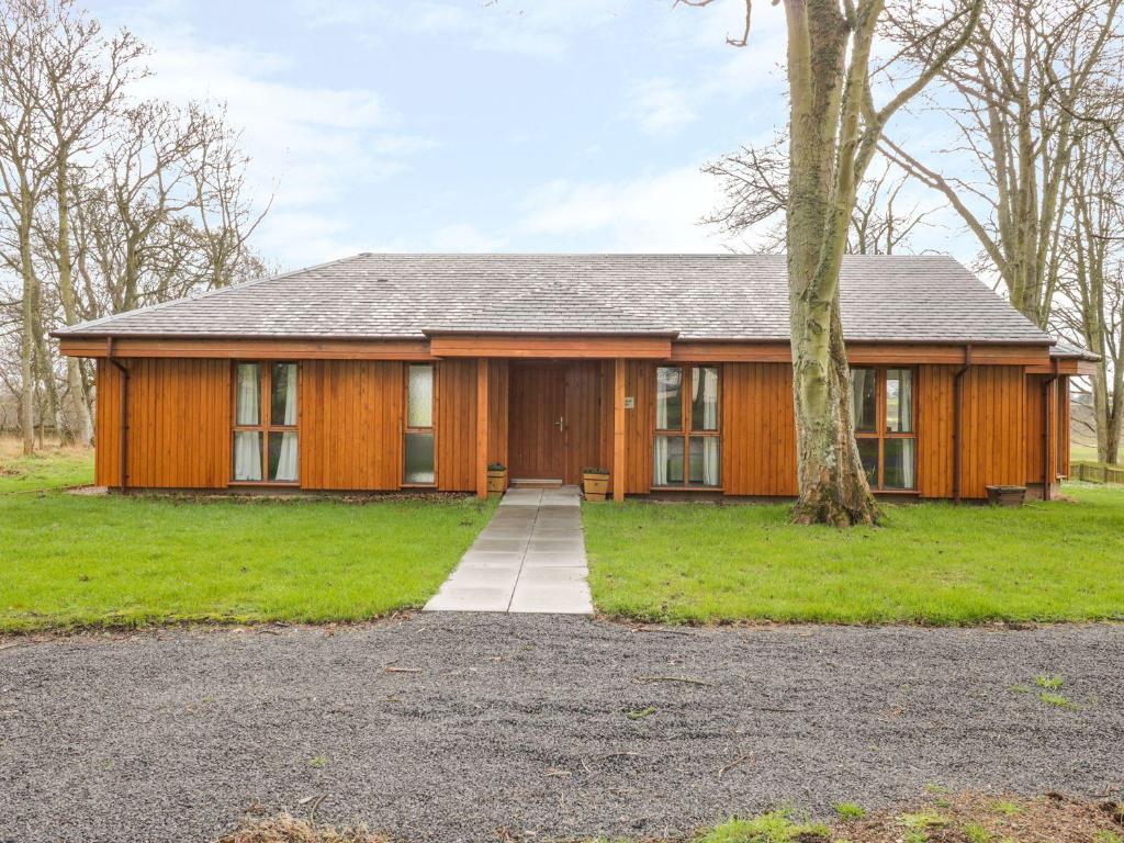 a wooden house with a tree in front of it at Blackadder Lodge in Duns